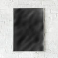 Sort abstrakt plakat med minimalistisk design hængende på hvid murstensvæg.