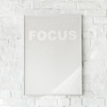 Minimalistisk plakat med ordet “FOCUS” gentaget i falmede hvide nuancer på en ren baggrund. Inspirerer til koncentration og ro.